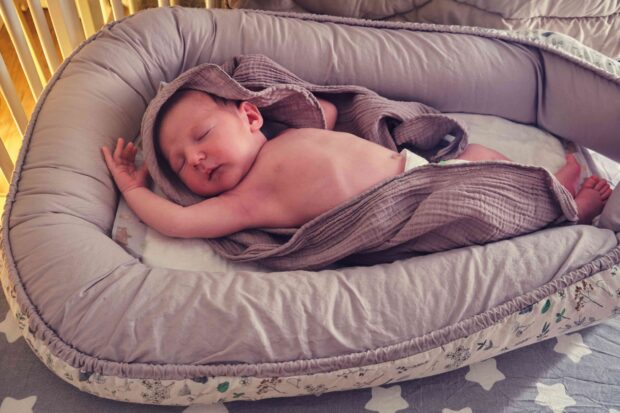 Baby schläft in einem Babynest.